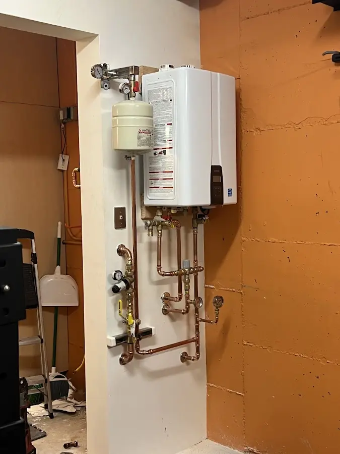 Plumbing technician inspecting water heater connections in Chittenango